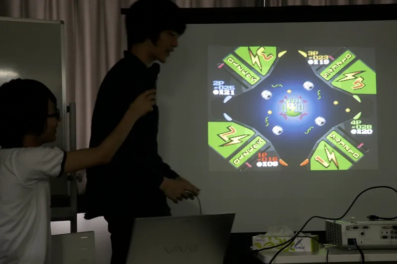 スクリーンの前で生徒が発表している写真
